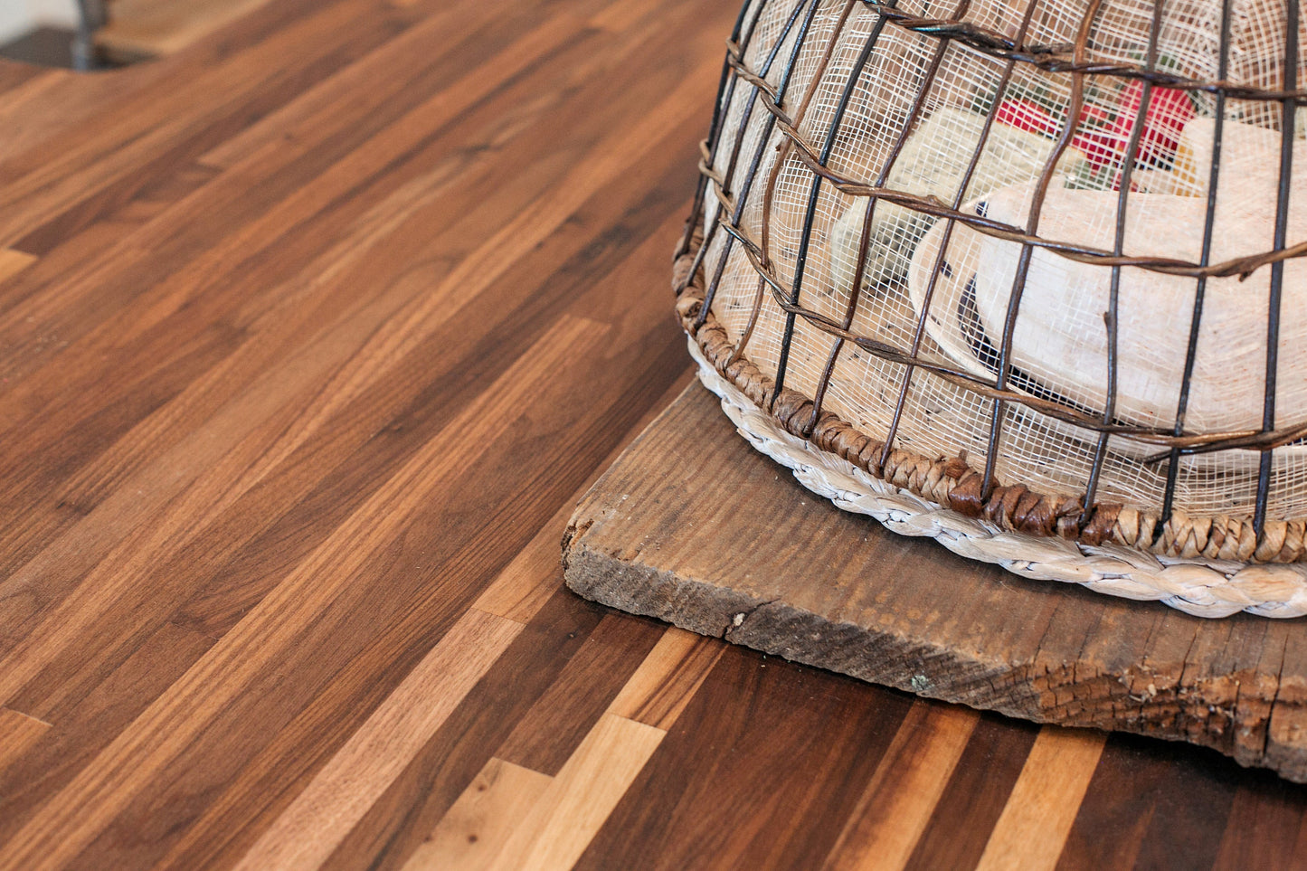 Close up of walnut countertop with a cheese board covered with a woven cloche