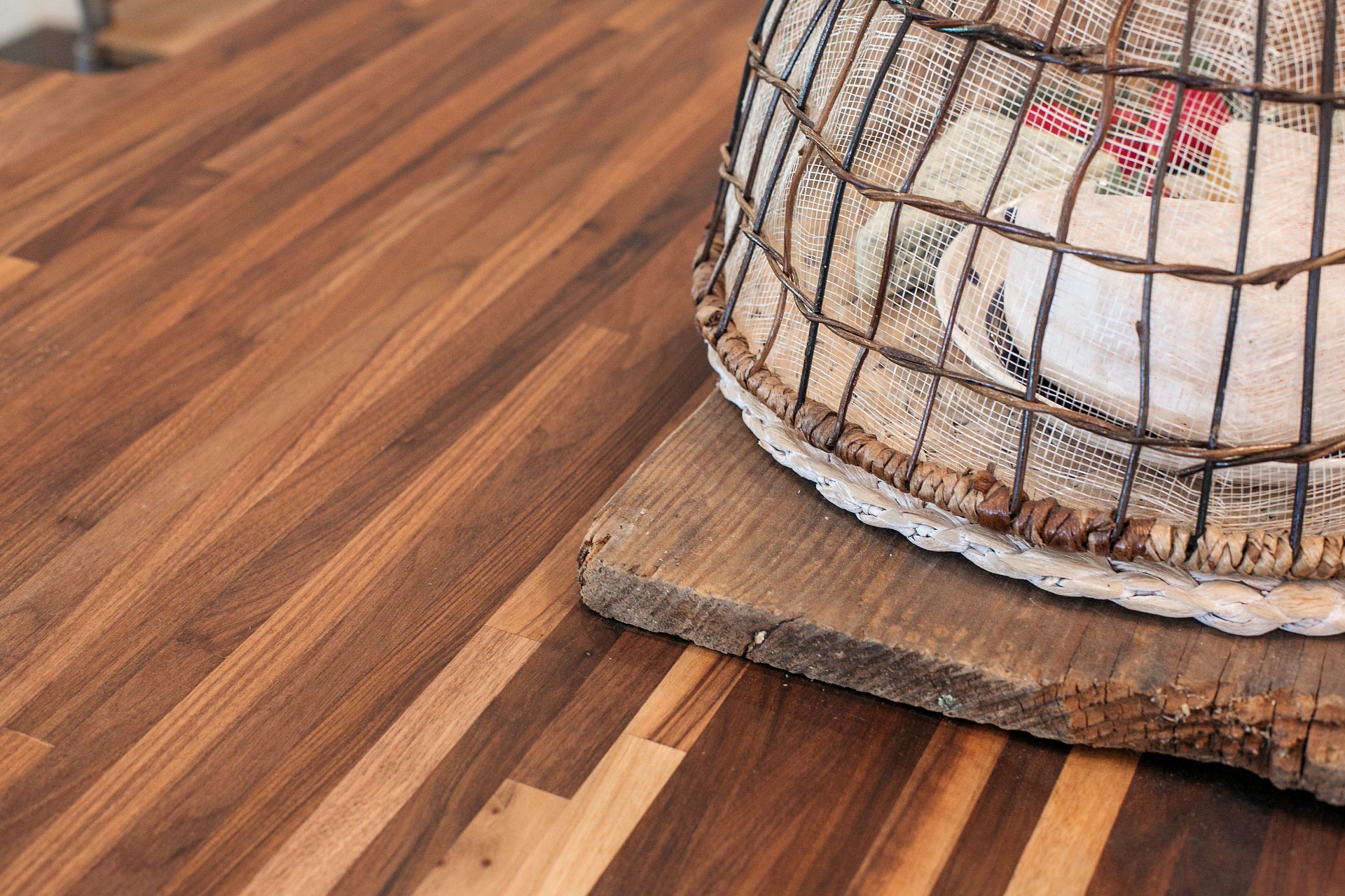 Close up of walnut countertop with a cheese board covered with a woven cloche